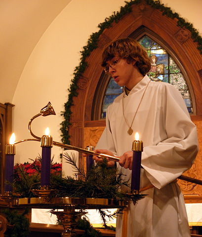 An acolyte lighting Advent candles